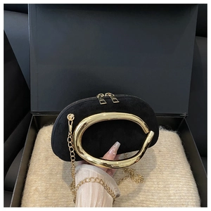Close-up of black suede evening clutch featuring a gold C-shaped handle and chain strap