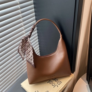 Brown leather crescent hobo bag with printed silk scarf handle on vintage background