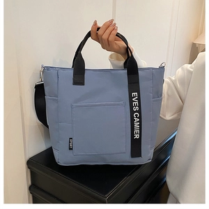 Detail of light blue lunch tote bag featuring EVES CAMIER printed straps and sport label
