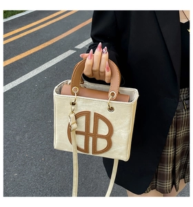 Détail du sac cabas contrasté avec logo monogramme HB et bandoulière réglable pratique
