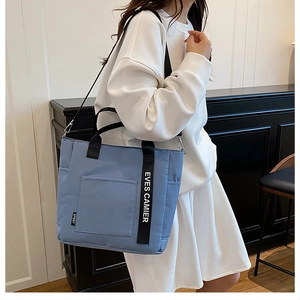 Detail of light blue canvas lunch bag with black straps and adjustable shoulder strap