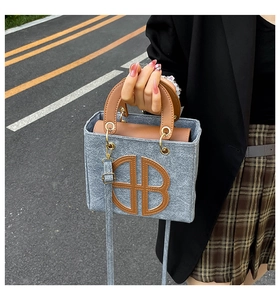 Détail du sac cabas en feutre gris avec anses en cuir marron et grand logo rond