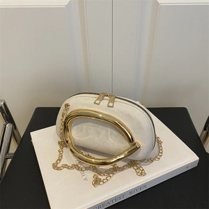 Minimalist cream oval evening clutch with gold metal handle and chain strap on book