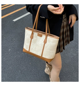 Detail of cream canvas tote bag with caramel leather straps and fashion leather patch