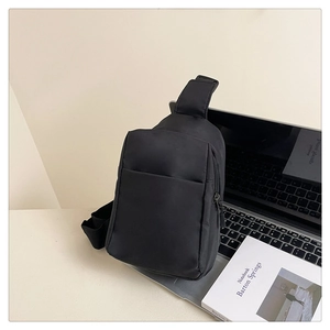 Detail of minimalist black nylon chest bag showing texture, zippers and side pocket
