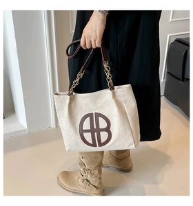 Detail of off-white tote bag with brown circular logo and chain leather handles