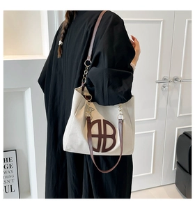 Detail of canvas tote bag with brown B-logo and gold chain shoulder strap