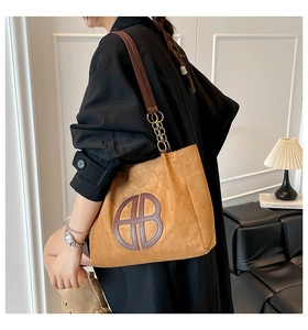 Detalle del bolso tote de ante con logo circular marrón y correa de cadena oro