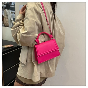 Detail of rose pink square handbag with knotted handle and adjustable strap on model
