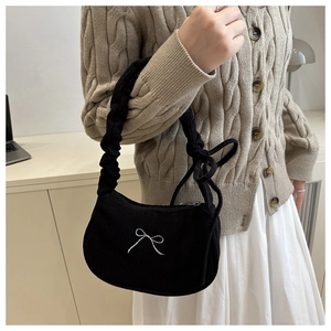 Detail of black corduroy shoulder bag with white bow embroidery and ruffled strap