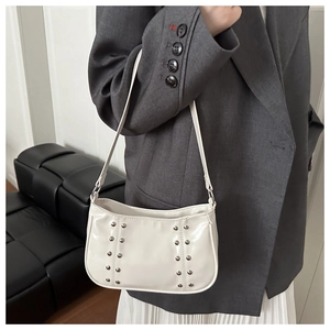 Detail of cream white faux leather underarm bag with decorative silver rivets on the side