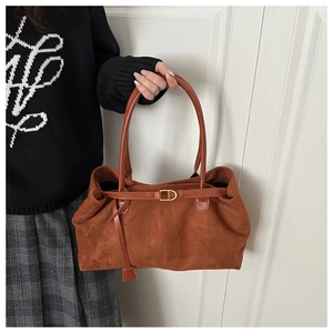 Close-up of caramel brown suede tote bag with decorative strap and D-ring detail