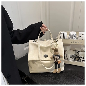 Detail of off-white tote bag with silver metal twist lock and cute bunny pendant