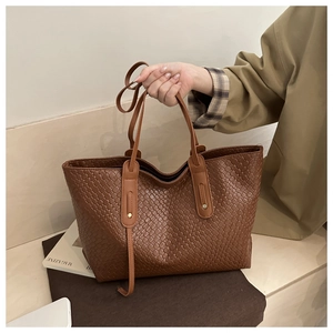 Detail of brown woven texture tote bag with elegant long decorative ribbon on the handle