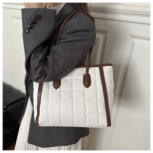 Detail of white quilted tote bag with brown straps worn with a stylish grey blazer