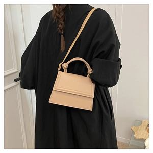 Detail of street style beige crossbody bag with knotted handle and trapezoid structure