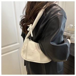 Detail of white corduroy shoulder bag featuring a pink bow embroidery and knotted strap