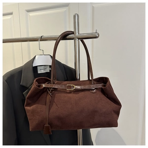 Detail of brown suede tote bag with golden D-ring buckle and glossy leather straps