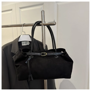 Detail view of a large black suede tote bag with leather handles and gold metal buckle