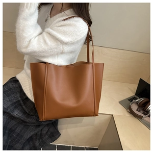 Close-up of brown faux leather tote bag showing fine texture and long shoulder straps