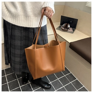 Brown large capacity faux leather tote bag being carried by hand in a lifestyle setting