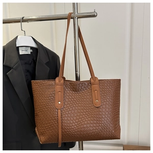 Close-up of woven caramel brown tote bag with premium PU texture and gold rivet details