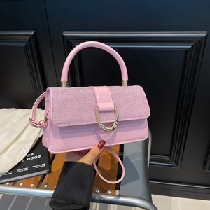 Pink crossbody bag with sequined flap and golden U-shaped buckle on a fashion model