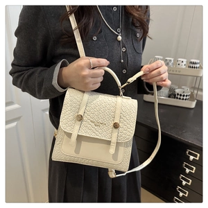 Détail du sac bandoulière blanc crème avec texture tissée, boucles dorées et bandoulière