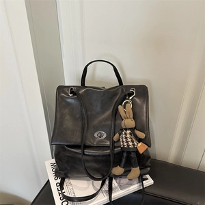 Vintage black leather tote bag with rabbit charm and metal lock on minimal magazines