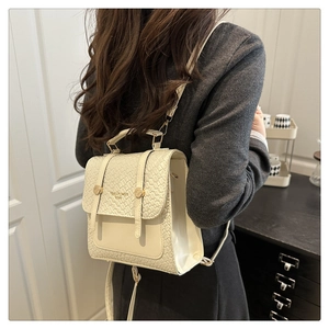 Rear view of a model wearing a beige woven flap backpack with gold hardware details