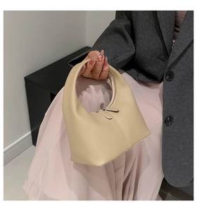 Detail of cream beige leather handbag featuring a fashion stamp and smooth zipper closure