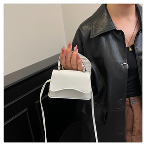 Gros plan d'un mini sac à bandoulière blanc en cuir avec rabat arrondi sur un modèle