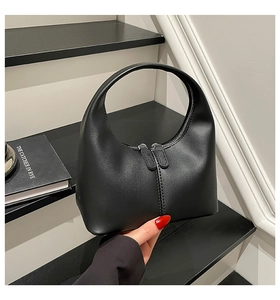 Detail of a black crescent hobo bag featuring contrast stitching and dual metal zippers