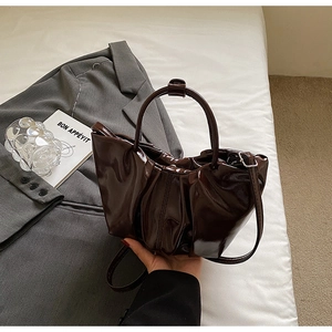 Detailed close-up of coffee brown pleated cloud bag with glossy patent leather finish