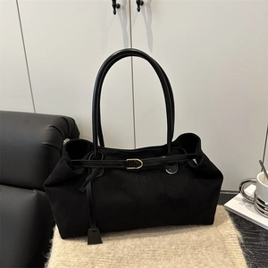 Chic black oversized suede tote bag with golden hardware buckle on a cozy knit backdrop