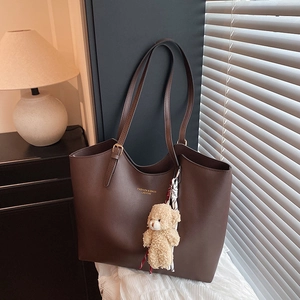 Vintage dark brown leather tote bag with plush bear charm and striped scarf accessory