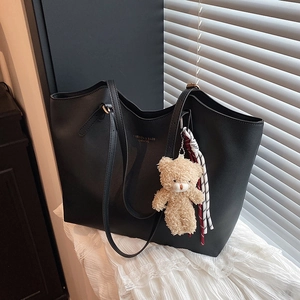 Retro large black leather tote bag with bear charm on a white lace background