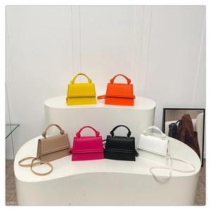 Multiple colorful leather crossbody bags displayed with unique knotted handle design