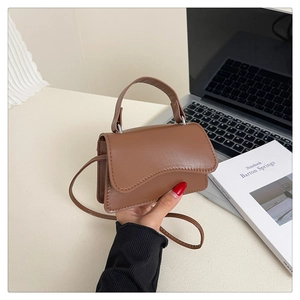 Détail du mini sac à main marron caramel avec rabat ondulé et texture en cuir