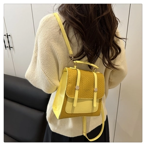 Detail of yellow crocodile embossed backpack with adjustable straps on model