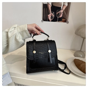 Detailed view of the black retro handbag featuring woven texture and gold metal buckles