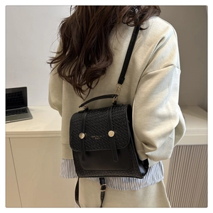 Close-up of black retro backpack featuring woven texture flap and metallic buckle