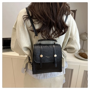 Detail of British vintage black mini backpack with woven texture and gold metal buckles