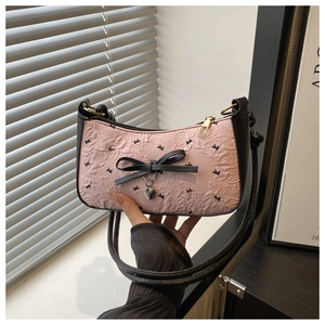 Detail of pink floral pleated fabric with black bow and heart metal charm on handbag