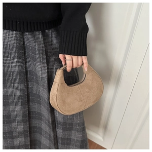 Detail of hobo bag with suede texture, crescent shape, and smooth metal zipper closure