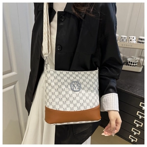 Macro detail of monogram leather texture and silver M logo on stylish crossbody bag