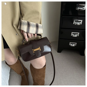 Detail view of dark coffee retro crossbody bag with golden buckle and sleek leather texture
