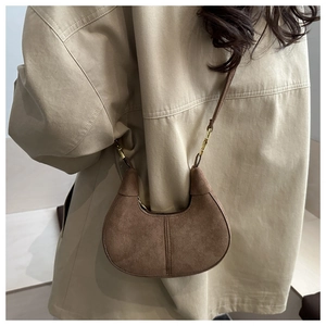 Detailed view of a vintage brown suede half-moon bag with elegant golden hardware details