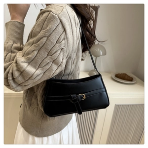 Minimalist black leather underarm bag with knot detail and golden buckle on model