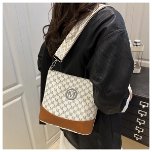 Detail of printed bucket bag with letter M pattern, wide strap and leather trim